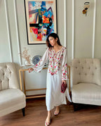 Side profile of model in ivory floral lawn suit holding maroon clutch