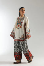Wide-leg printed trousers featuring tribal black-white pattern and red floral border