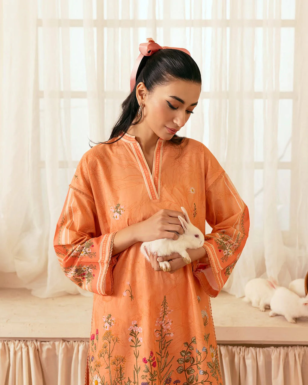 Woman in peach orange digital printed 2-piece suit holding a white bunny